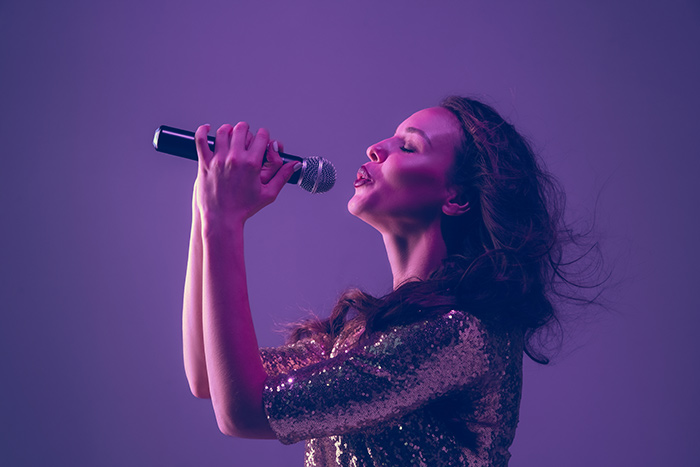 Lady lifting up the microphone and singing