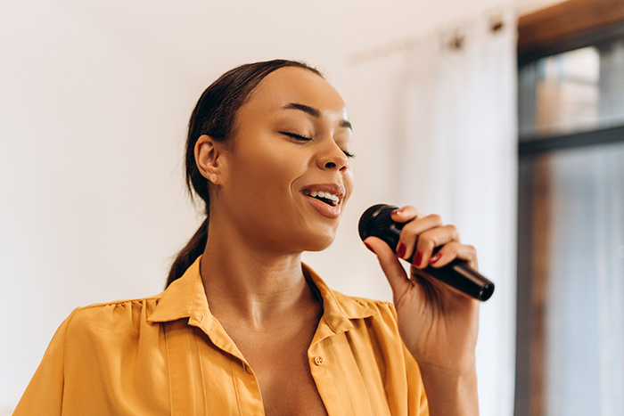 Lady with yellow blouse singing with microphone